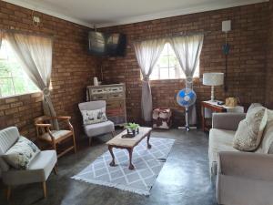 een woonkamer met een bank, stoelen en een tafel bij Oppieplaas in Alldays