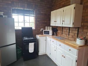 een keuken met witte kasten en een zwarte koelkast bij Oppieplaas in Alldays