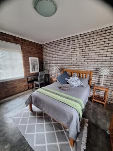 een slaapkamer met een groot bed en een bakstenen muur bij Oppieplaas in Alldays