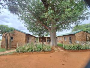 een bakstenen gebouw met een boom ervoor bij Oppieplaas in Alldays