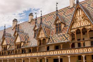 an ornate building with a tile roof with windows at Alfred Hotels Beaune La Madeleine in Beaune
