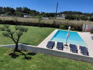 een zwembad met 4 stoelen en een parasol bij Correia Villa in Barcelos