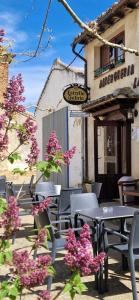 a patio with tables and chairs and pink flowers at Albergue Laganares - Exclusivo para peregrinos in San Nicolás del Real Camino