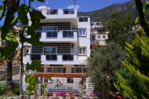 a white apartment building with a mountain in the background at Neruda Hotel in Kalkan