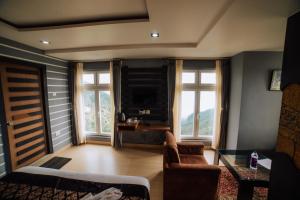 a living room with a couch and a table and windows at Amarjeet Hotel in Kurseong