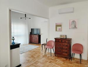 een woonkamer met 2 stoelen, een bureau en een televisie bij Correia Villa in Barcelos