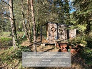 a sign in front of a wooden structure in the woods at SHROOM & WATER chill calm nature 2 houses 8 person in Nowe Grobice +2 photos