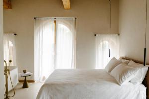 a bedroom with a white bed with two windows at La Ghiandaia Farmhouse in Conegliano