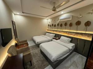 a hotel room with two beds and a tv at The Luxe Nook in Islamabad