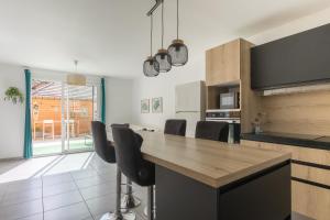 a kitchen with a wooden table and black chairs at Morgon Garden Lodge - Proche de la Rivière in Savines