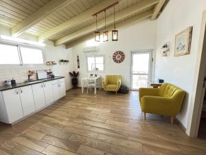 a kitchen with white cabinets and yellow chairs and a table at A Place To Remember in Ma‘alot