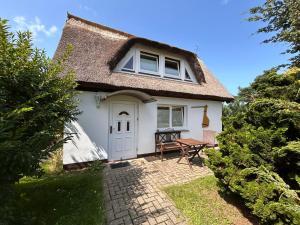a small white cottage with a thatched roof at Ferienhaus Brise - Schmugglerhus in Wieck