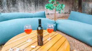 a bottle of wine and two glasses on a table at Coliving moderno com lindo jardim in Porto