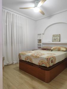 una camera da letto con un letto e un ventilatore a soffitto di Apartamento 700 metros de la playa a Playa Flamenca