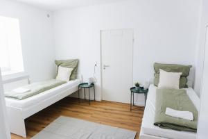 a white room with two beds and two tables at Ferienwohnung Zur Wieskapelle W3 - ideal für Monteure in Straubing