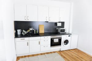 a kitchen with white cabinets and a washer and dryer at Ferienwohnung Zur Wieskapelle W3 - ideal für Monteure in Straubing