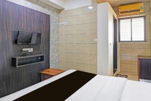 a bedroom with a bed and a tv on a wall at Hotel RK in Ahmedabad