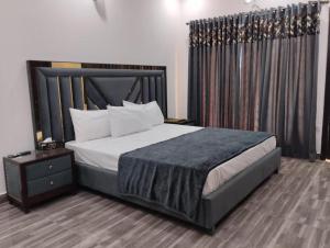 a bedroom with a large bed with a black headboard at Doolv Guest House in Islamabad