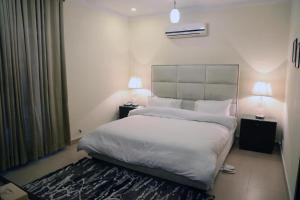 a bedroom with a large white bed with two lamps at Doolv Guest House in Islamabad +15 photos