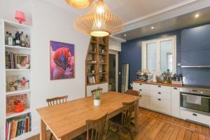 a dining room with a wooden table and a kitchen at Spacious apartment near the Villette in Paris +10 photos