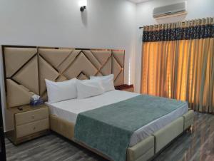 a bedroom with a large bed with a large headboard at Doolv Guest House in Islamabad