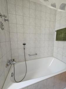 eine weiße Badewanne mit Dusche im Badezimmer in der Unterkunft Ferienland Sonnenwald Ferienwohnung im Sonnenwald Apartment 5 in Langfurth 