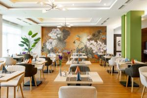ein Restaurant mit Tischen und Stühlen und einem Wandgemälde in der Unterkunft Hotel Aurora in Miskolctapolca