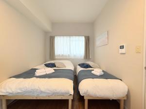 two twin beds in a room with a window at Cooee Chigasaki 406 in Chigasaki