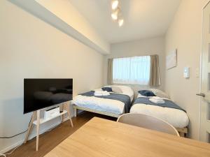 a room with two beds and a flat screen tv at Cooee Chigasaki 406 in Chigasaki