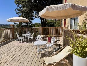 a wooden deck with chairs and tables and umbrellas at Le Patio Tursan in Pimbo