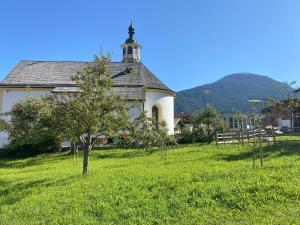 an old church with a tree in the middle of a field at WEIDE SUITES Stubaital - Adults Only in Schönberg im Stubaital