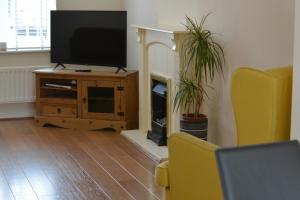 a living room with a flat screen tv on a wooden cabinet at 5 Holborn Spacious Home in Redhill
