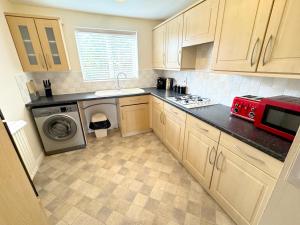 a kitchen with wooden cabinets and a red appliance at 5 Holborn Spacious Home in Redhill