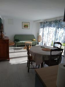 a living room with a table and a green couch at Chez Louise in Arboussols