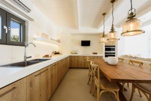 a kitchen with a wooden table and a sink at Noble Pearl Villas Paros in Santa Maria