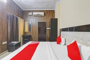 a bedroom with a white bed with red pillows at Hotel O Four Square in Lucknow