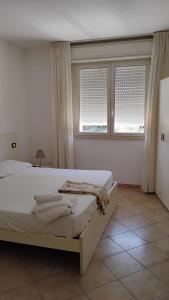 a white bedroom with a bed and two windows at Residence il Tombolo in Principina a Mare