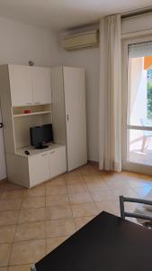 a living room with white cabinets and a television at Residence il Tombolo in Principina a Mare