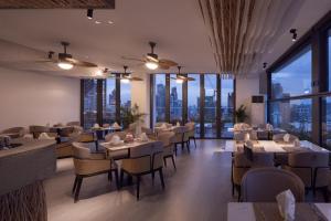 a restaurant with tables and chairs and large windows at Bassac Signature Hotel & Residence in Phnom Penh