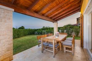 a patio with a table and chairs under a wooden pergola at Villa Amalija in Krmenjak