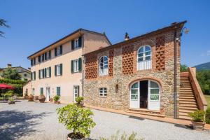 a large brick building with white doors and windows at Villa al Falchetto by VacaVilla in Capannori