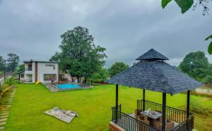 a house with a large umbrella in a yard at SaffronStays Fernshade - 3BR Khopoli retreat, patio, lawn picnics & riverside walks, quick Mumbai access via Atal Setu in Jambhulpāda