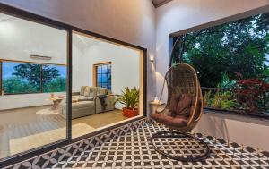 a room with a rattan chair and a living room at SaffronStays Fernshade - 3BR Khopoli retreat, patio, lawn picnics & riverside walks, quick Mumbai access via Atal Setu in Jambhulpāda +25 photos