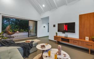 a living room with a tv and a couch at SaffronStays Fernshade - 3BR Khopoli retreat, patio, lawn picnics & riverside walks, quick Mumbai access via Atal Setu in Jambhulpāda