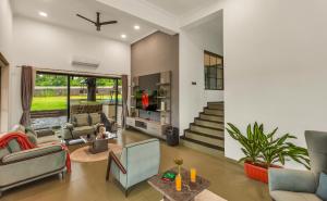 a living room filled with furniture and a staircase at SaffronStays Fernshade - 3BR Khopoli retreat, patio, lawn picnics & riverside walks, quick Mumbai access via Atal Setu in Jambhulpāda