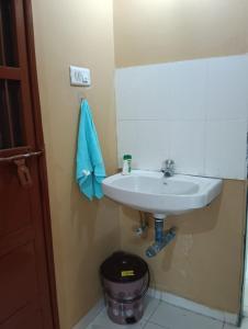 a bathroom with a white sink and a trash can at Mahi's HomeStay in Nashik