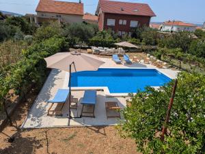 an overhead view of a swimming pool with an umbrella and chairs at Apartments Good Times with heated pool in Kaštela