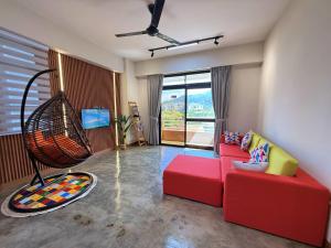 a living room with a red couch and a swing at The Almost Touching the Stars Suite in Genting Highlands