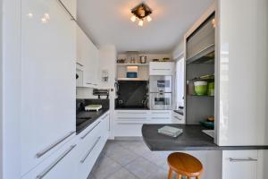 a kitchen with white cabinets and a wooden chair at Le Rev - à 900m de la plage in La Baule