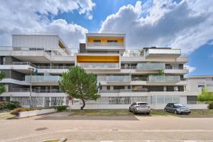 an apartment building with two cars parked in a parking lot at Le Rev - à 900m de la plage in La Baule